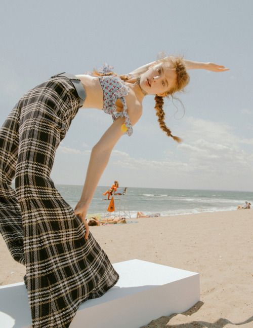 a woman is doing a hand stand on a bench on the beach