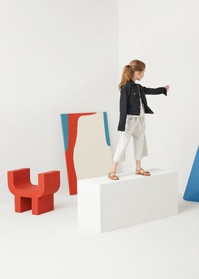 a little girl standing on top of a white block