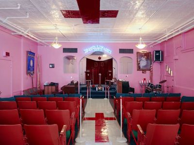 a room filled with red chairs and a pink wall