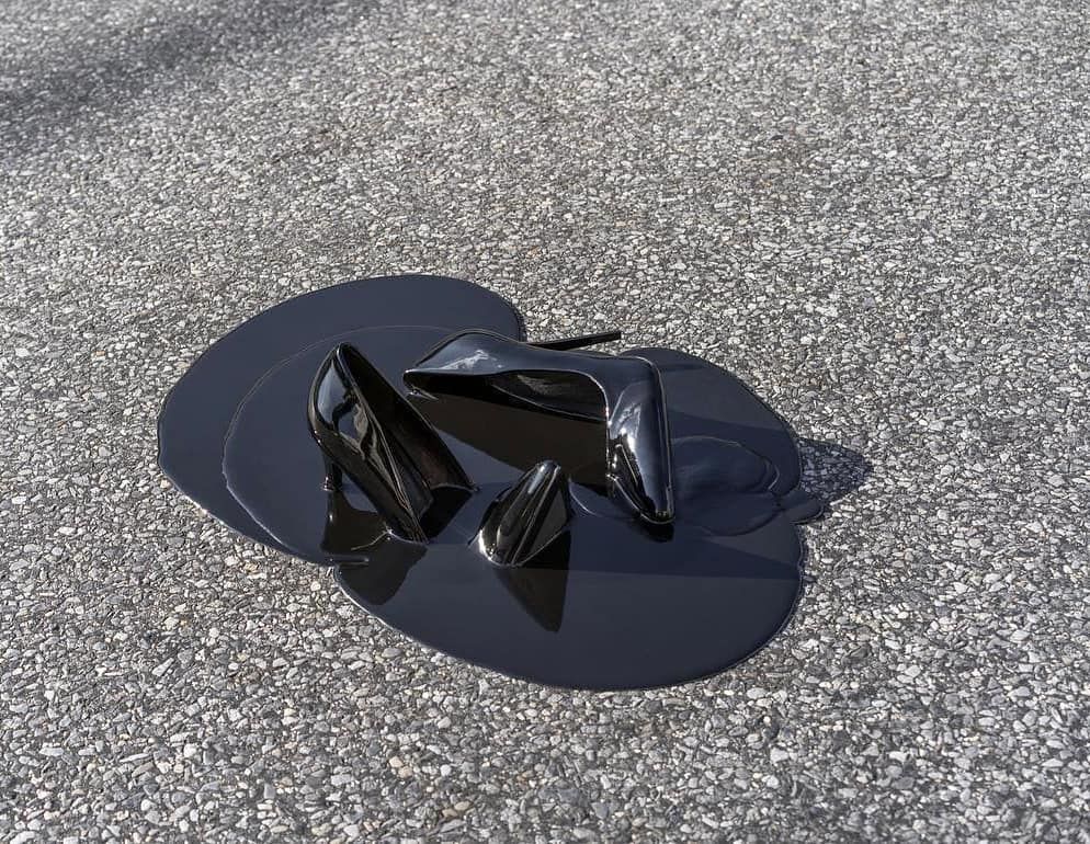 a pair of black shoes sitting on top of a puddle