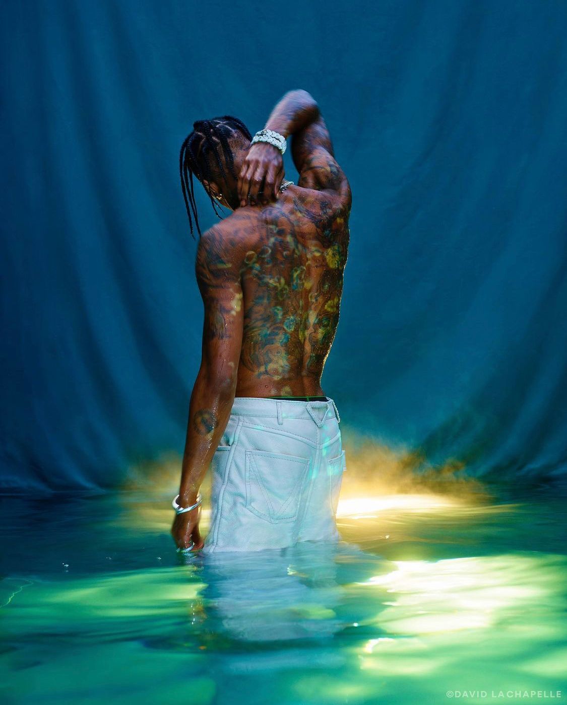 a man with tattoos standing in a body of water