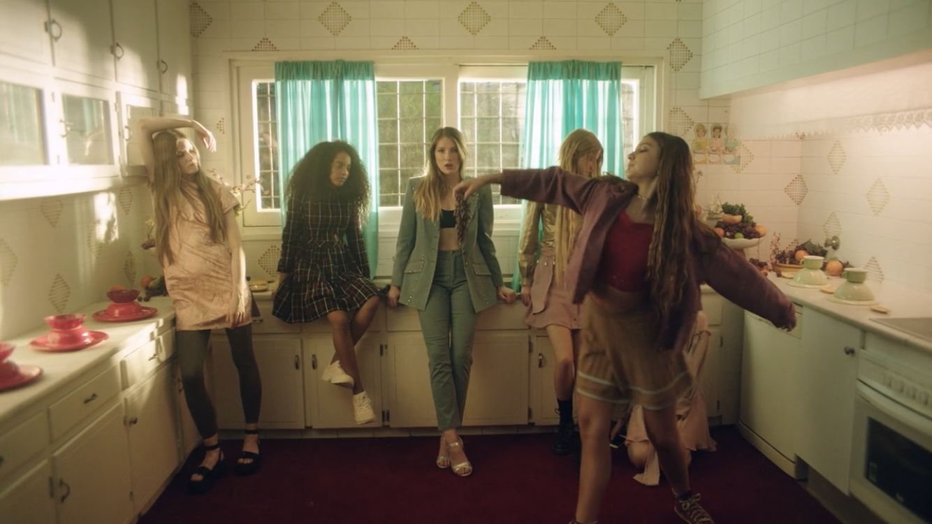 a group of young women standing in a kitchen