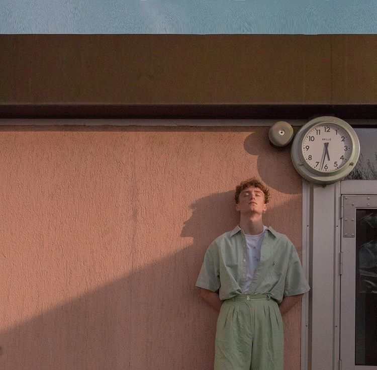 a man standing next to a wall with a clock on it