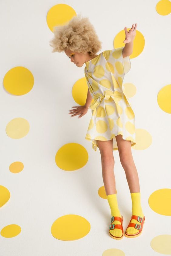 a little girl wearing yellow shoes and a yellow dress