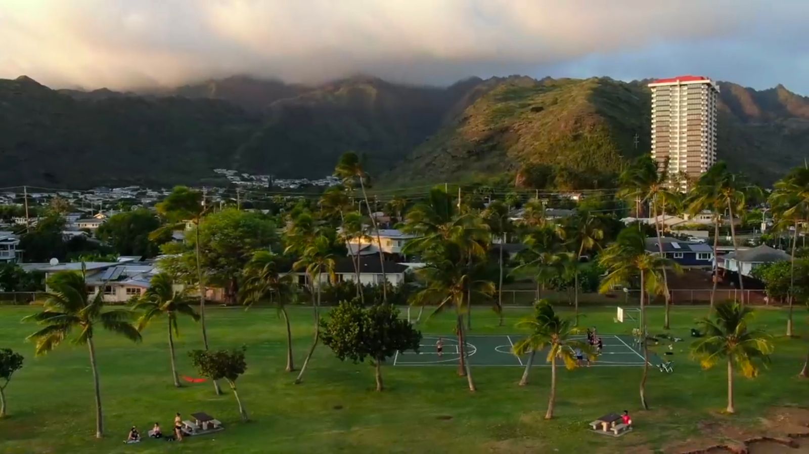 a tennis court surrounded by palm trees and mountains