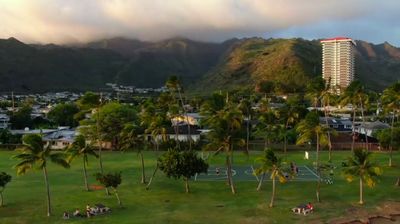 a tennis court surrounded by palm trees and mountains