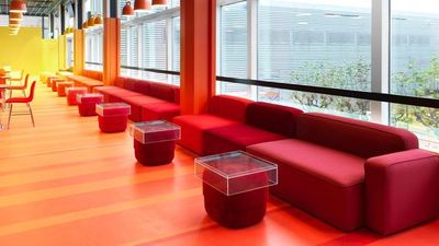 a room with a lot of red couches and tables