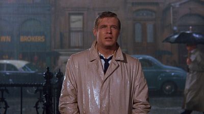 a man in a trench coat standing in the rain