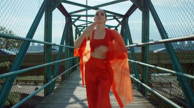 a woman in a red dress walking across a bridge