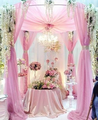 a pink and white wedding setup with flowers and a chandelier