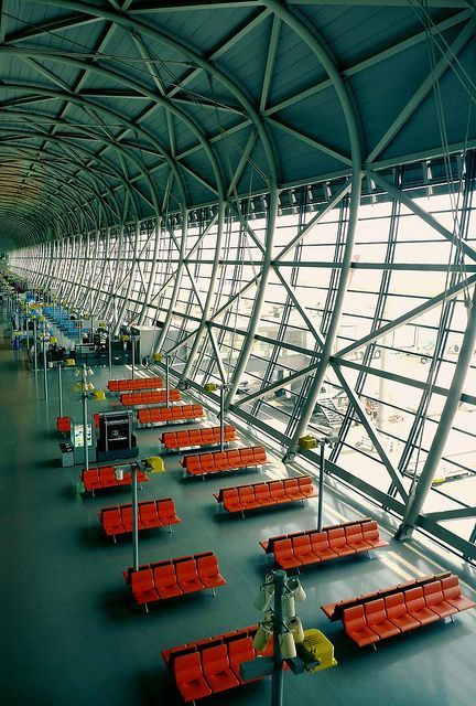 an airport terminal with rows of red seats