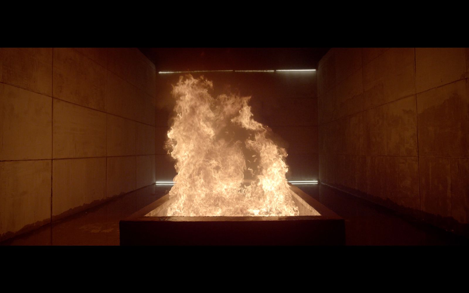 a fire burning inside of a room filled with cement walls