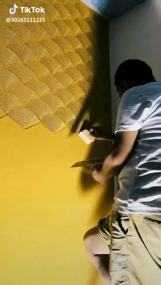 a man painting a wall with yellow paint