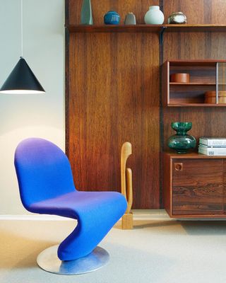 a blue chair sitting in a living room next to a book shelf