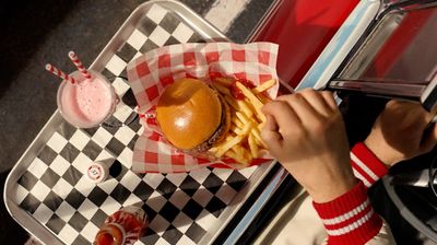 a person taking a picture of a hamburger and fries