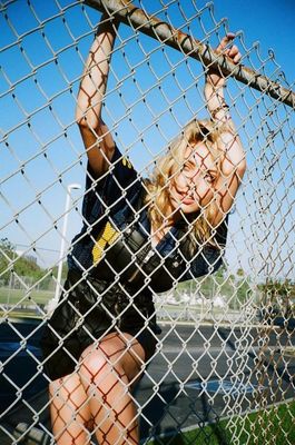 a woman holding a baseball bat behind a chain link fence