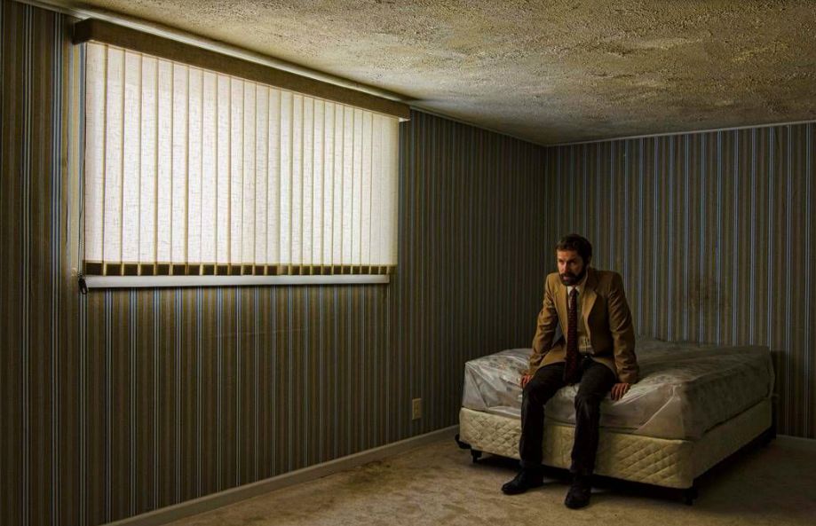 a man sitting on top of a bed in a room