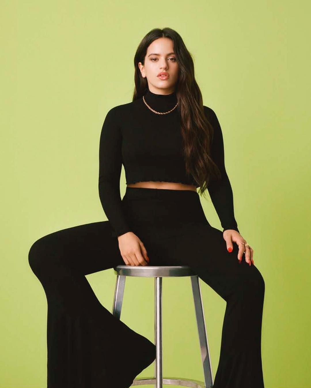 a woman sitting on a stool in a black outfit