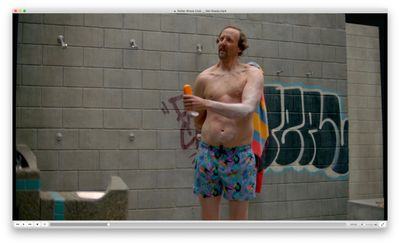 a shirtless man holding a frisbee in front of a wall