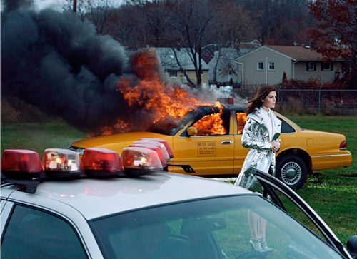 a woman standing in front of a car on fire