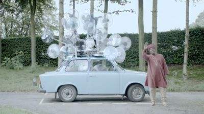 a person standing next to a car with a bunch of balloons on top of it