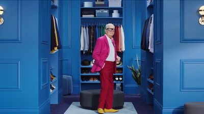 a man in a pink suit standing in a blue closet