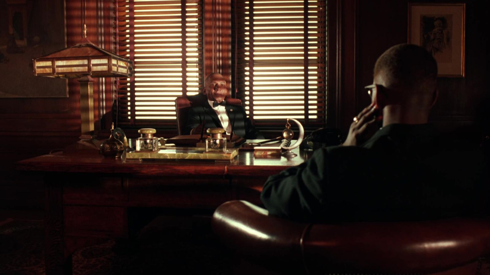 a man sitting at a desk talking on a cell phone