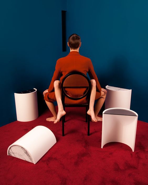 a man sitting on a chair surrounded by different types of furniture