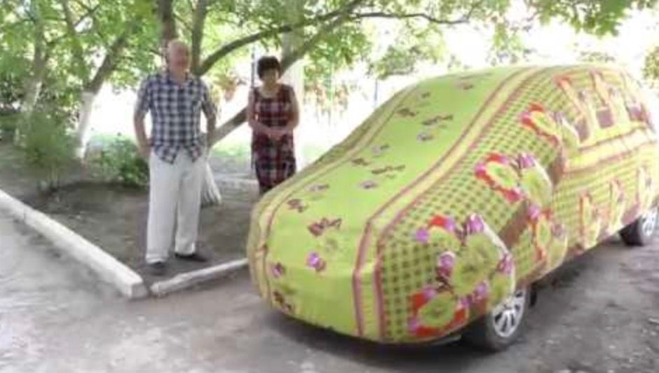 a man standing next to a car covered in a blanket