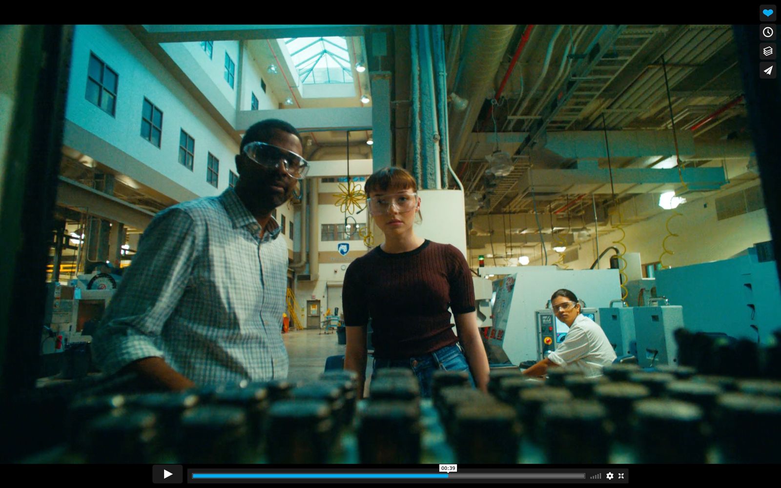 a man standing next to a woman in a factory