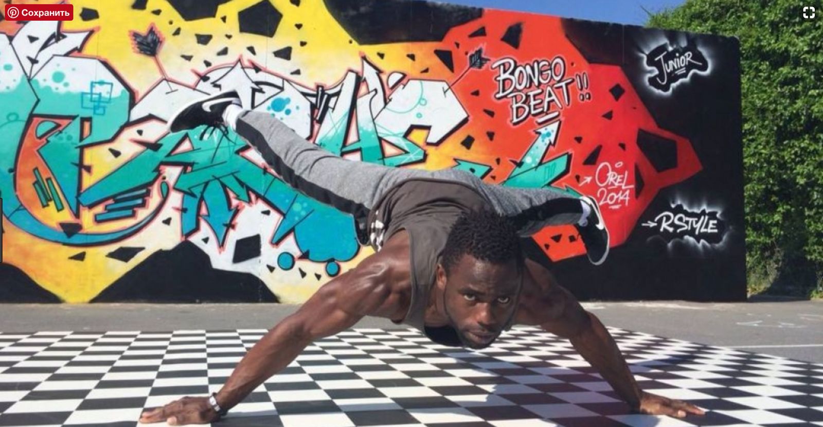 a man doing a handstand in front of a graffiti wall