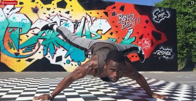 a man doing a handstand in front of a graffiti wall