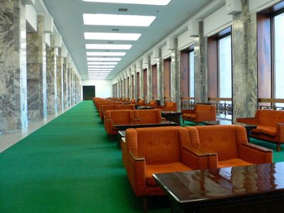 a long hallway with orange chairs and green carpet