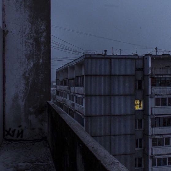 a tall building with a yellow light in the window