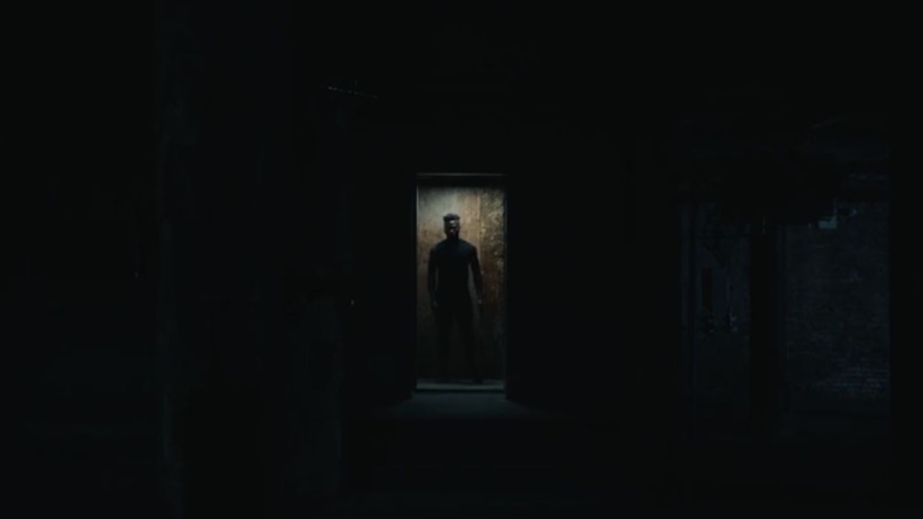 a man standing in a dark room with a creepy look on his face