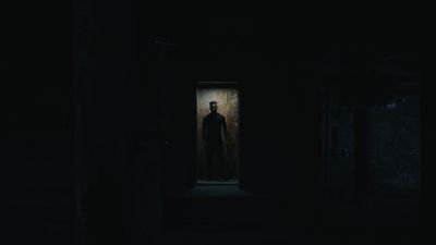 a man standing in a dark room with a creepy look on his face