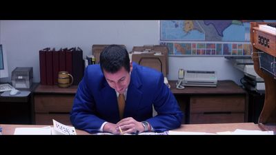 a man in a blue suit writing on a piece of paper