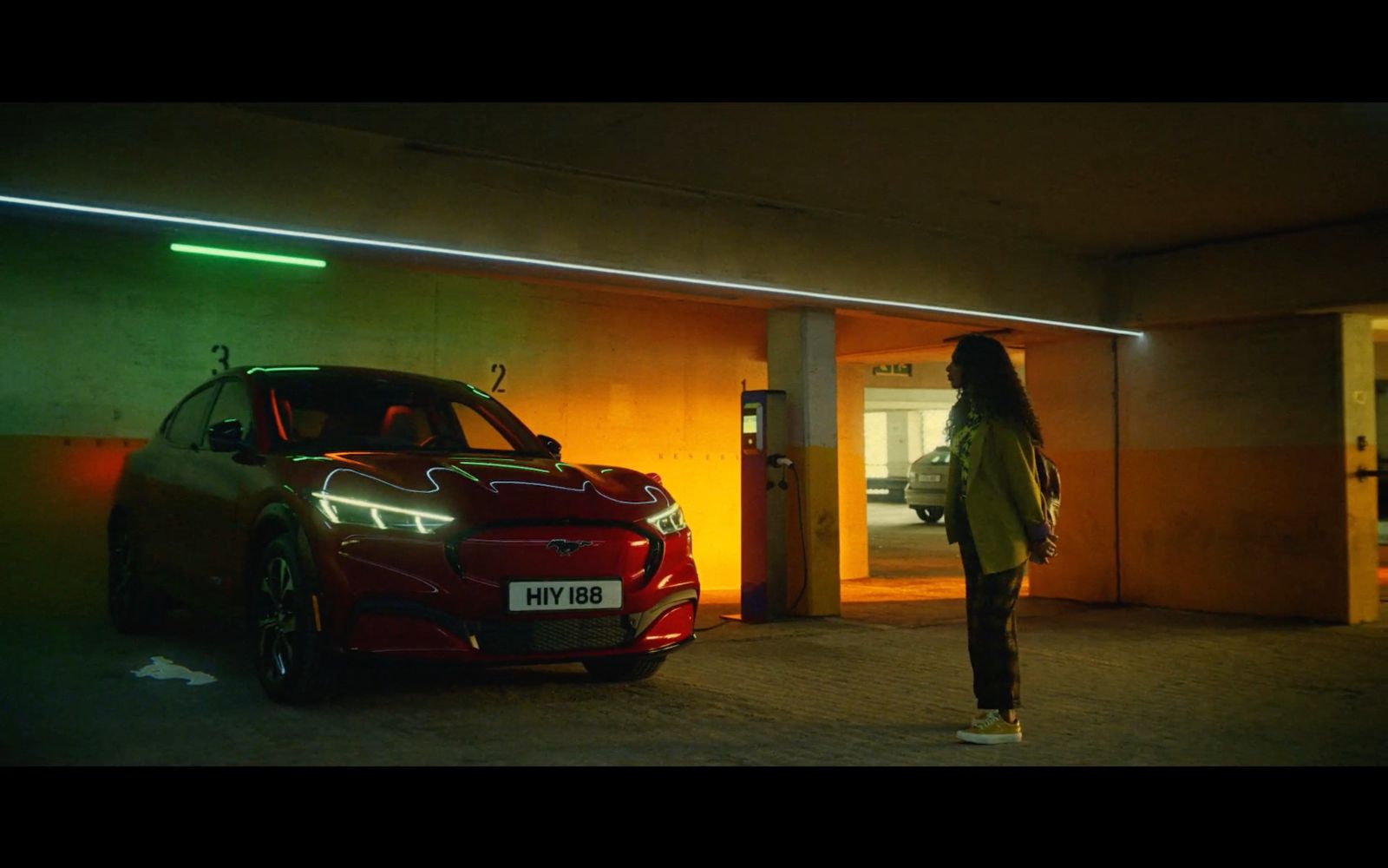 a woman standing next to a red car in a parking garage