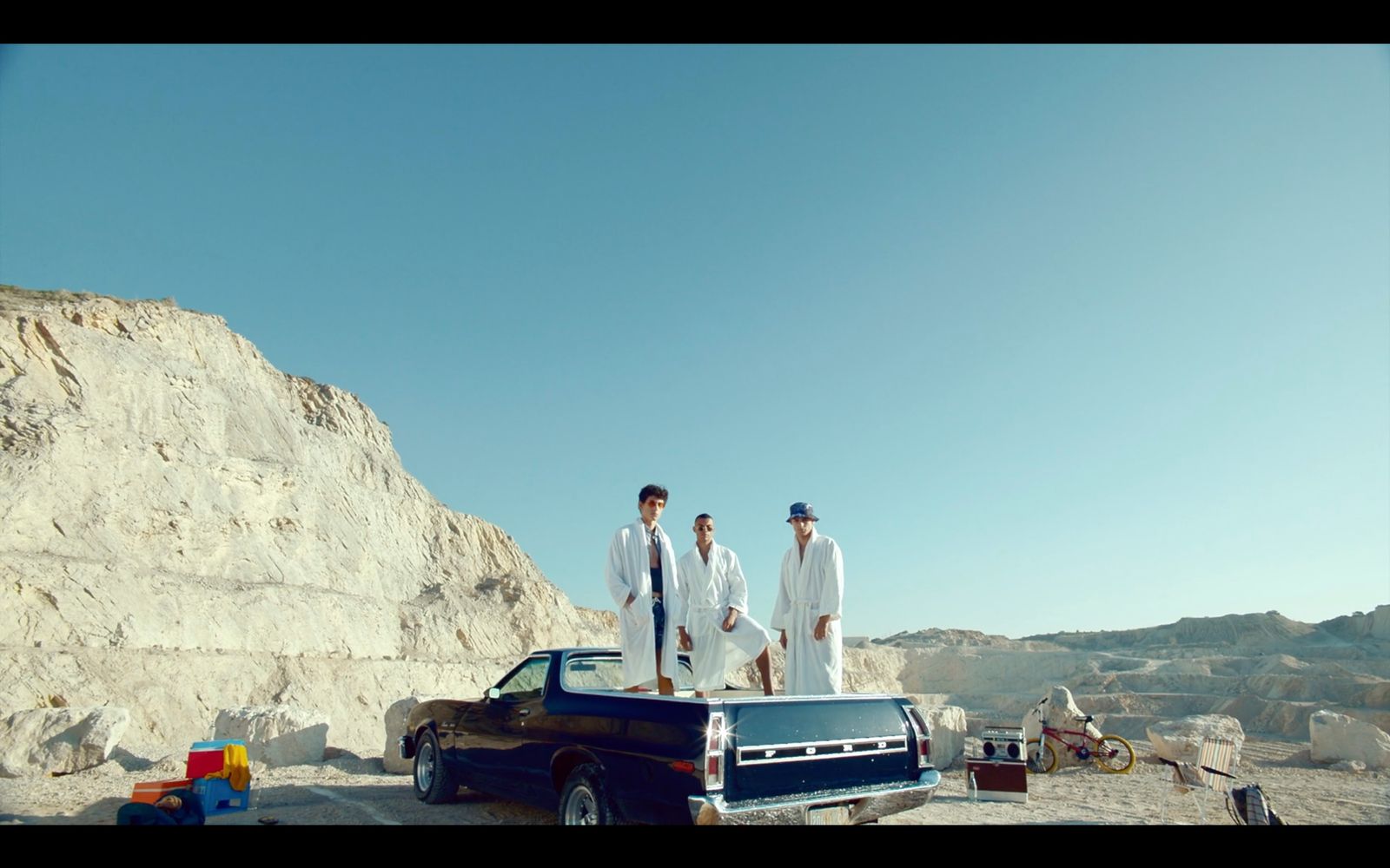 three men standing on the back of a pick up truck