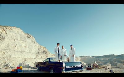 three men standing on the back of a pick up truck