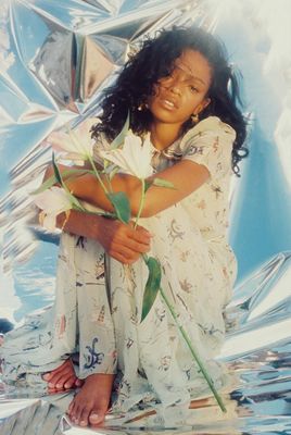 a woman sitting on a shiny surface holding a flower