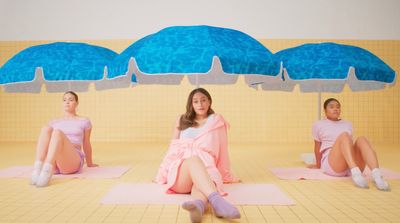 a group of women sitting on top of yoga mats under umbrellas