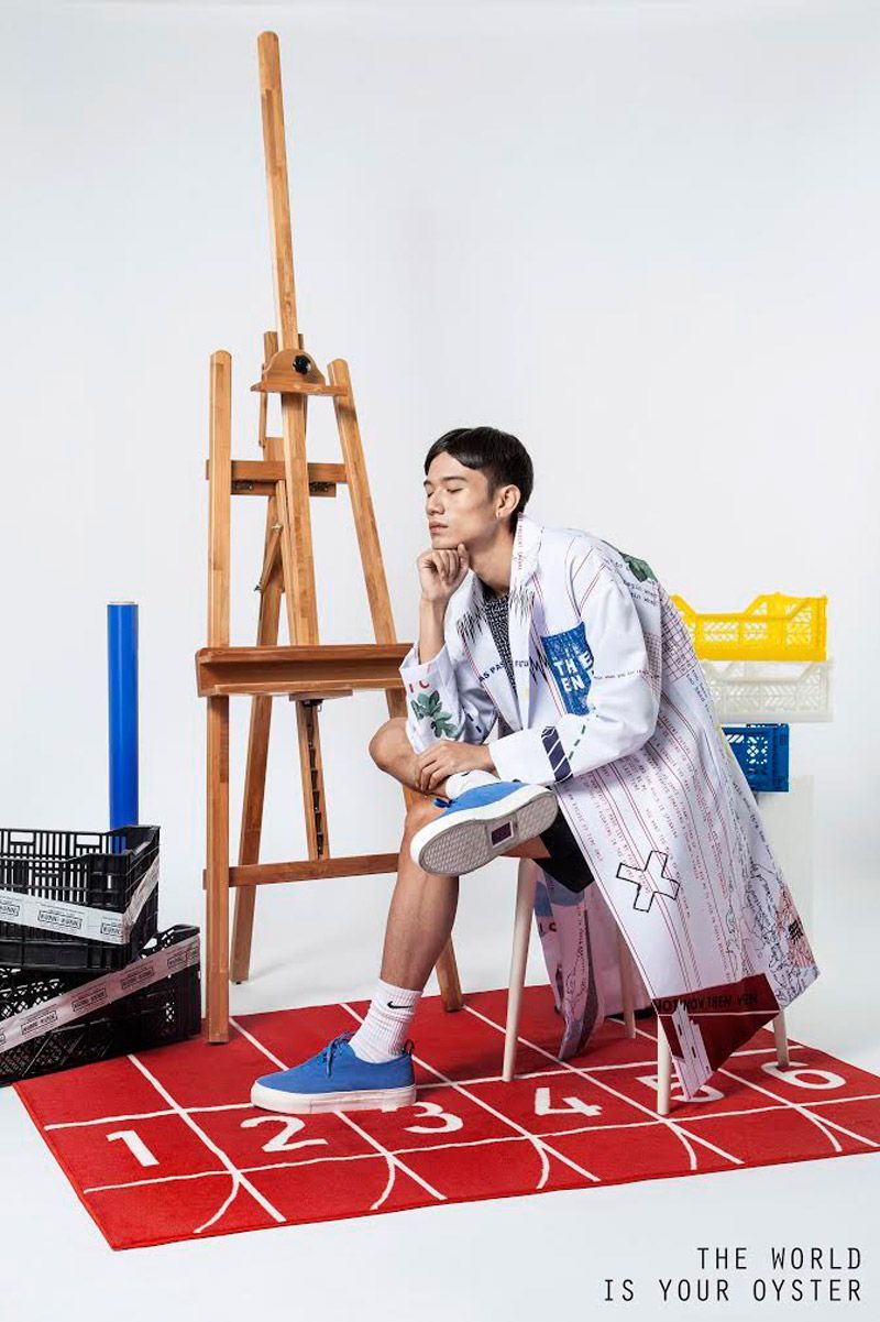 a man sitting on top of a red rug next to an easel