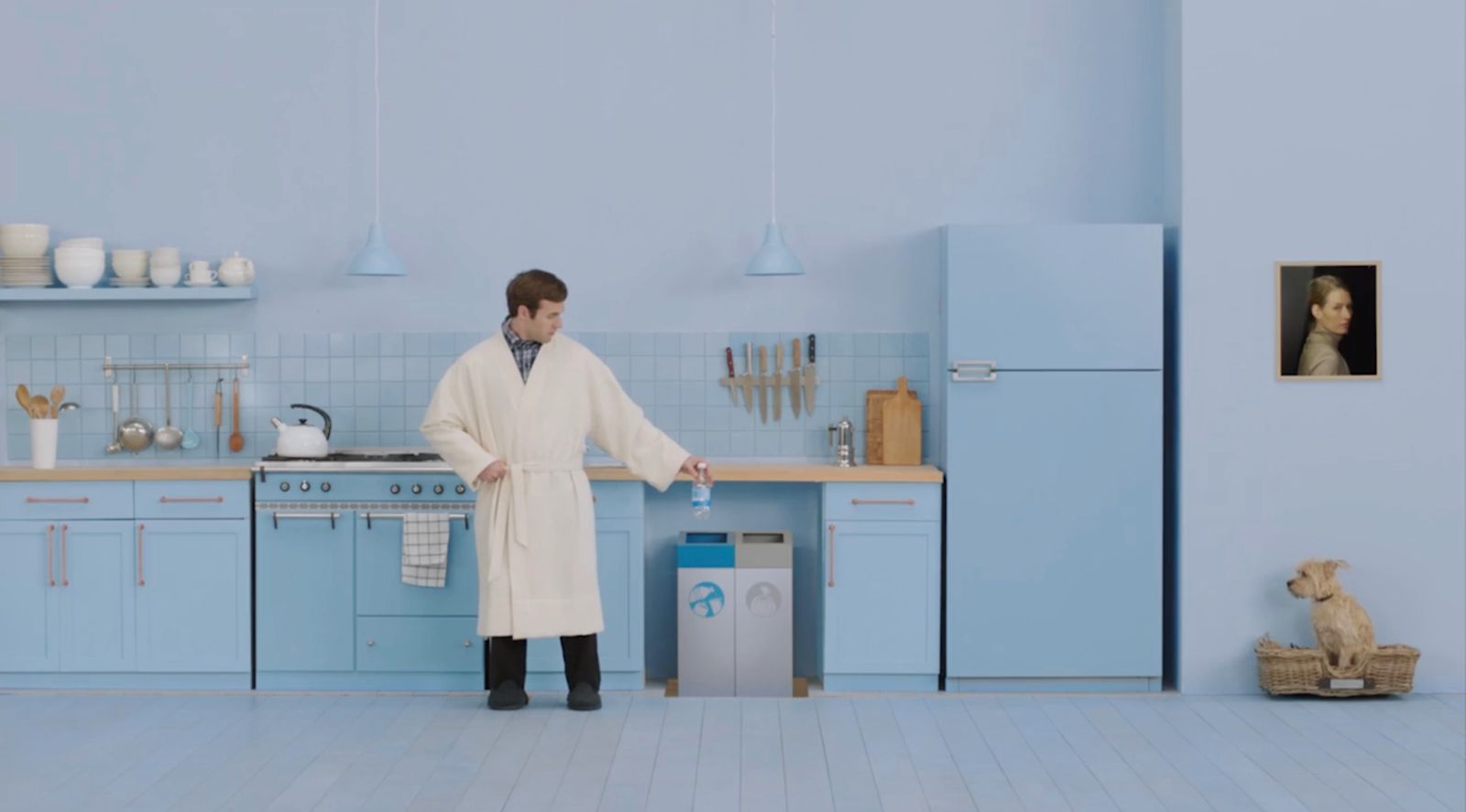 a man in a white coat standing in a blue kitchen