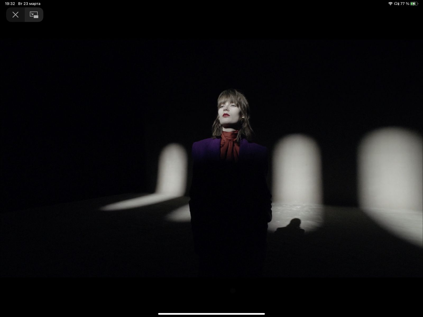 a woman standing in a dark room with a red scarf around her neck