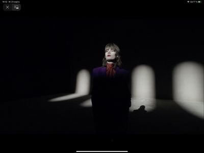 a woman standing in a dark room with a red scarf around her neck