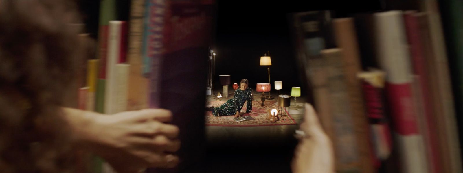 a woman is sitting on a chair in front of a bookshelf