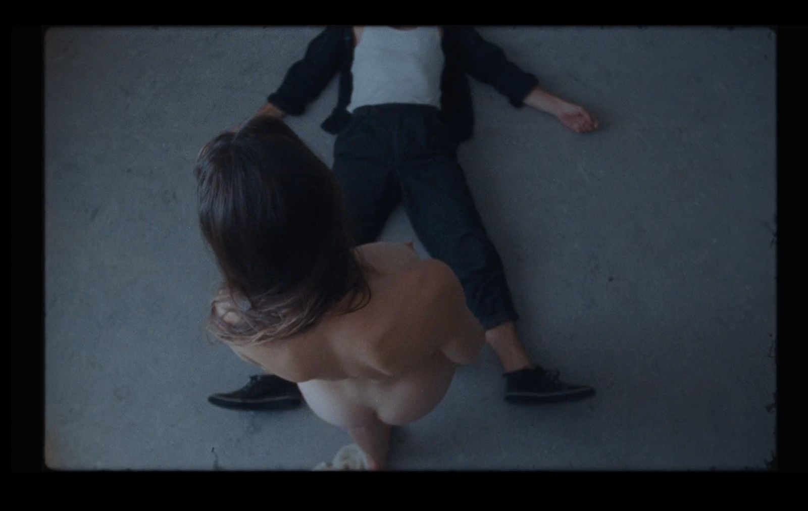 a naked woman laying on the ground next to a man