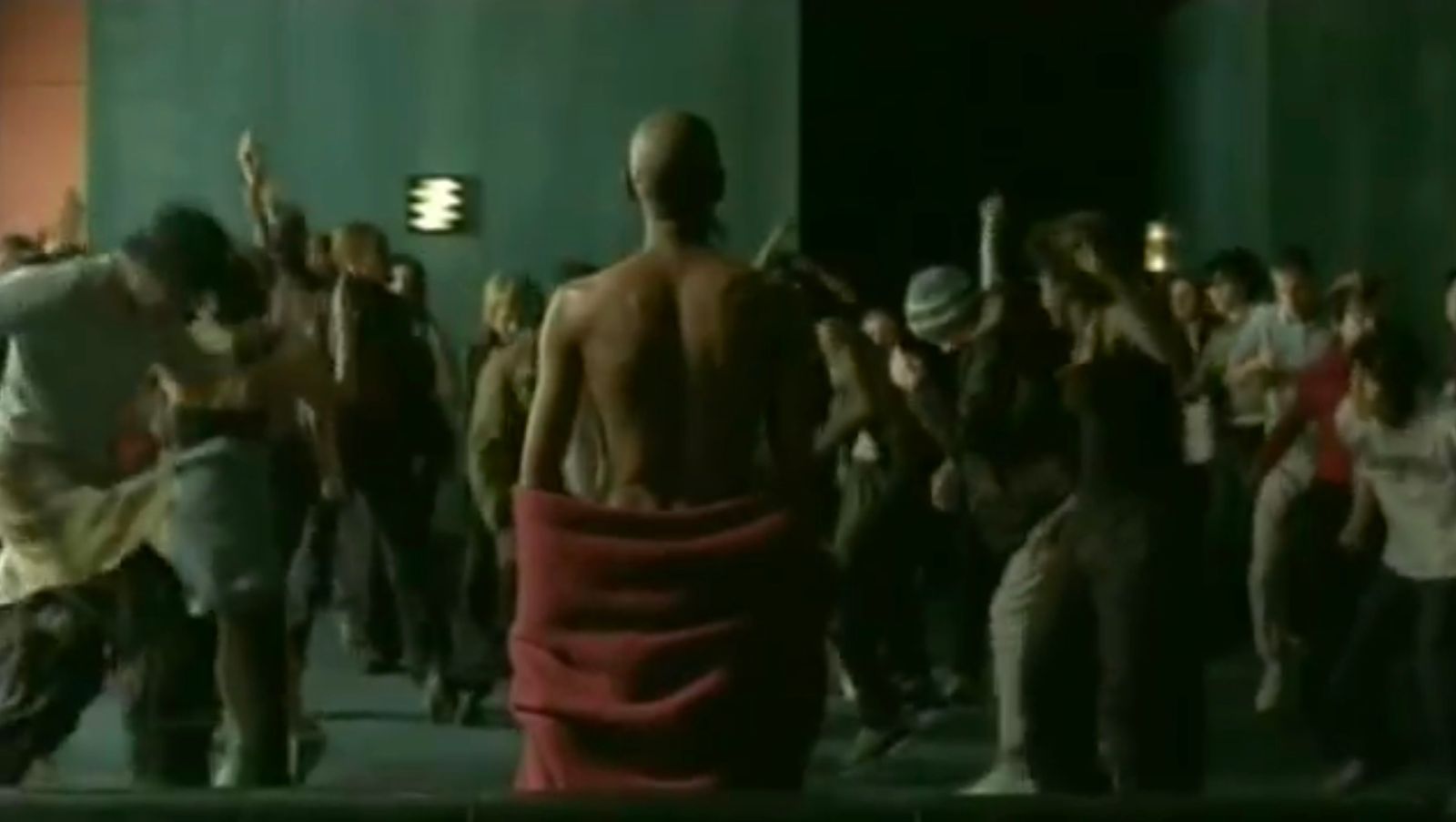 a crowd of people standing around a man in a red towel