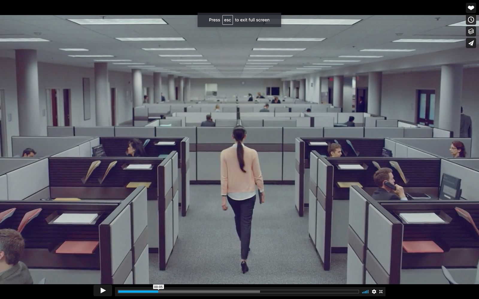 a woman walking through a room filled with cubicles